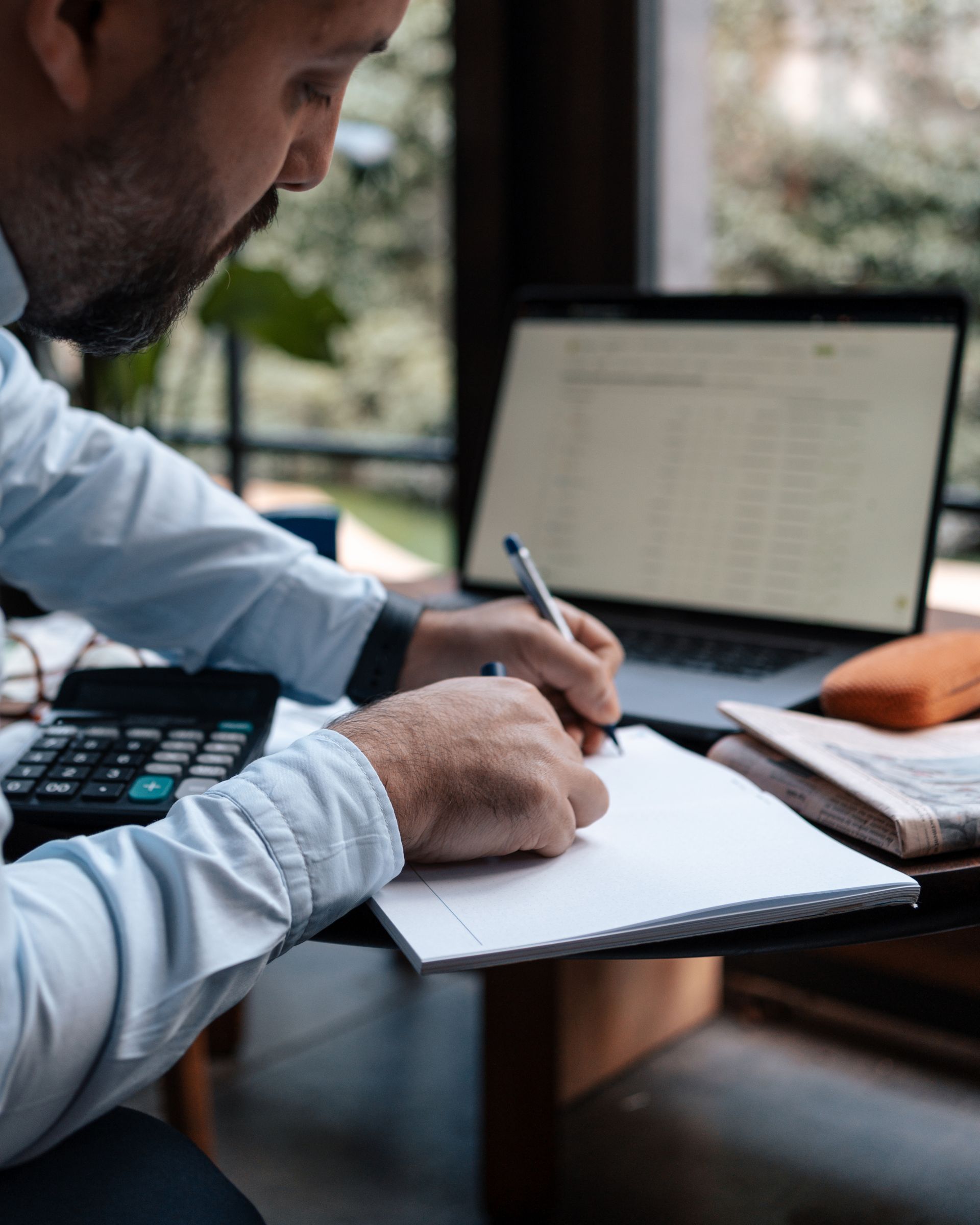 Un estimateur écrit dans un cahier devant un ordinateur portable et une calculatrice.